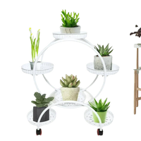 Black metal six-tier circular plant stand filled with potted plants indoors.