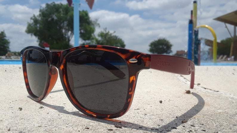 Close-up of tortoise frame sunglasses showing detailed artisan engraving on the temples.