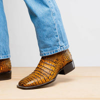 Side view of Tucson Mustard Brown boot worn with blue jeans outdoors on a stone surface.