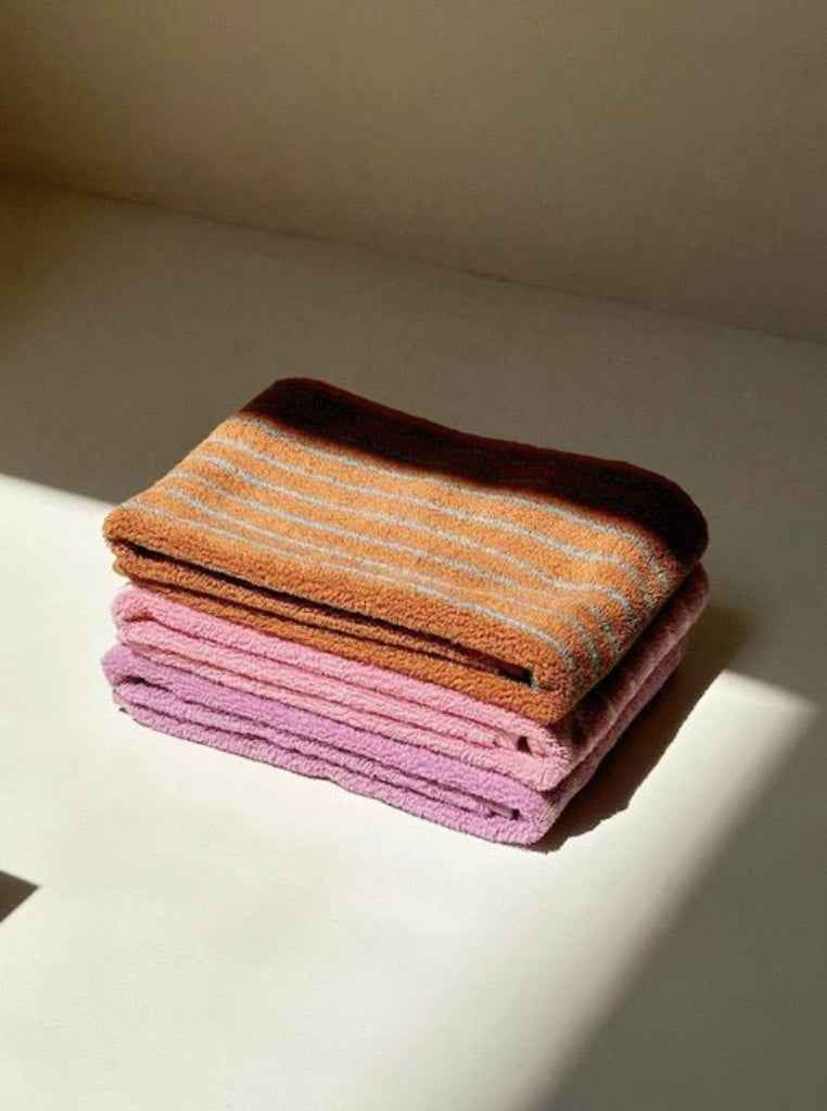 Bath towel with classic retro stripes spread out on surface, highlighting vibrant colors and plush softness.