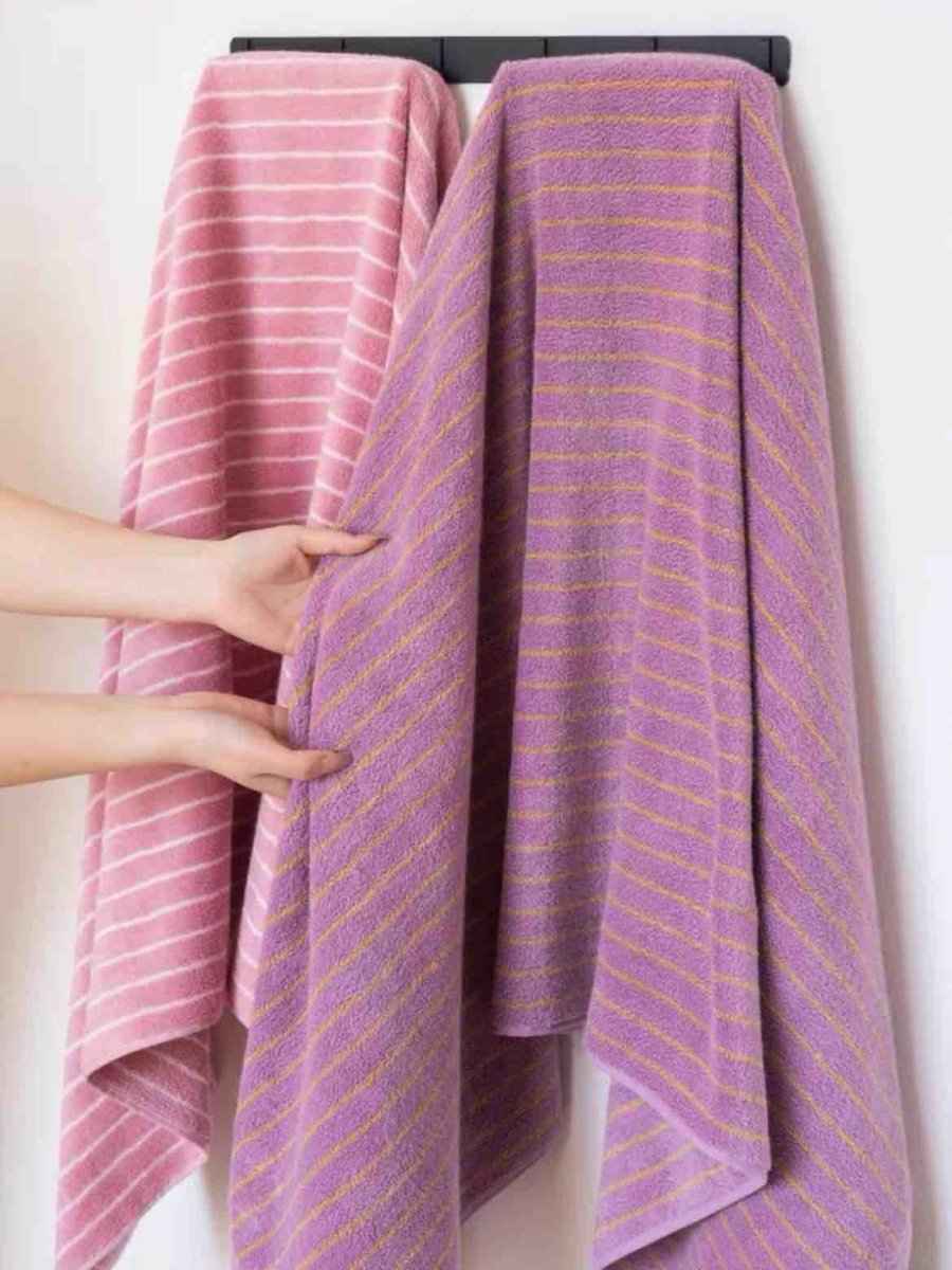 Retro stripe bath towel draped over a white bathtub edge, showcasing vibrant colors and soft fabric.