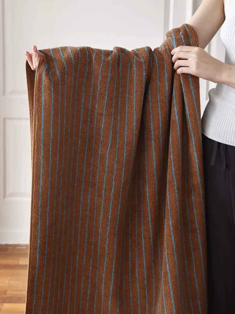 Close-up of retro-striped bath towel with warm tones highlighting plush, absorbent organic cotton fibers.
