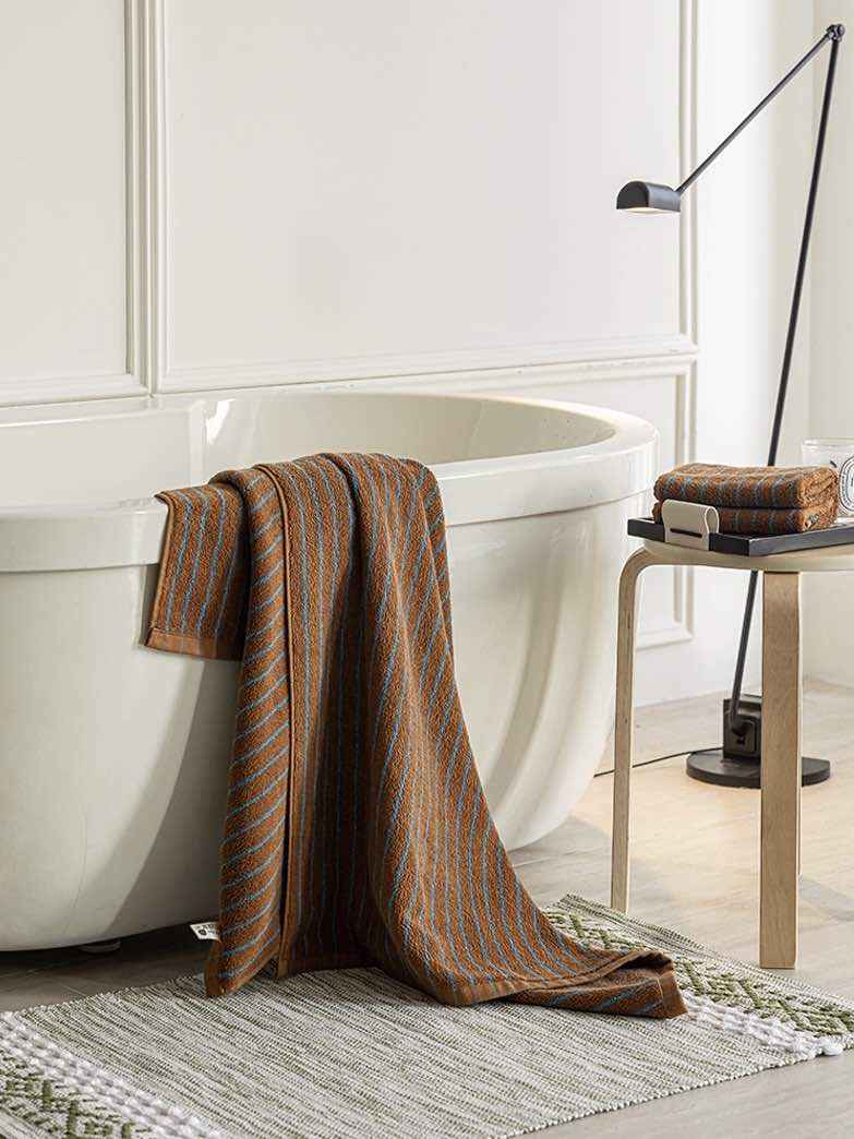 Stack of folded retro stripe bath towels with rich warm colors sitting on a wooden surface.