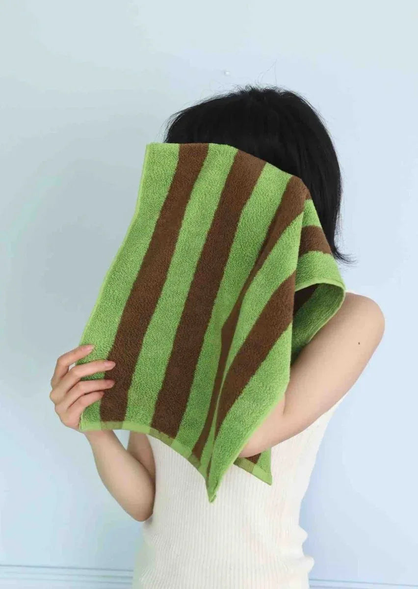 Soft combed cotton towel with bright, playful stripes draped over a chair.