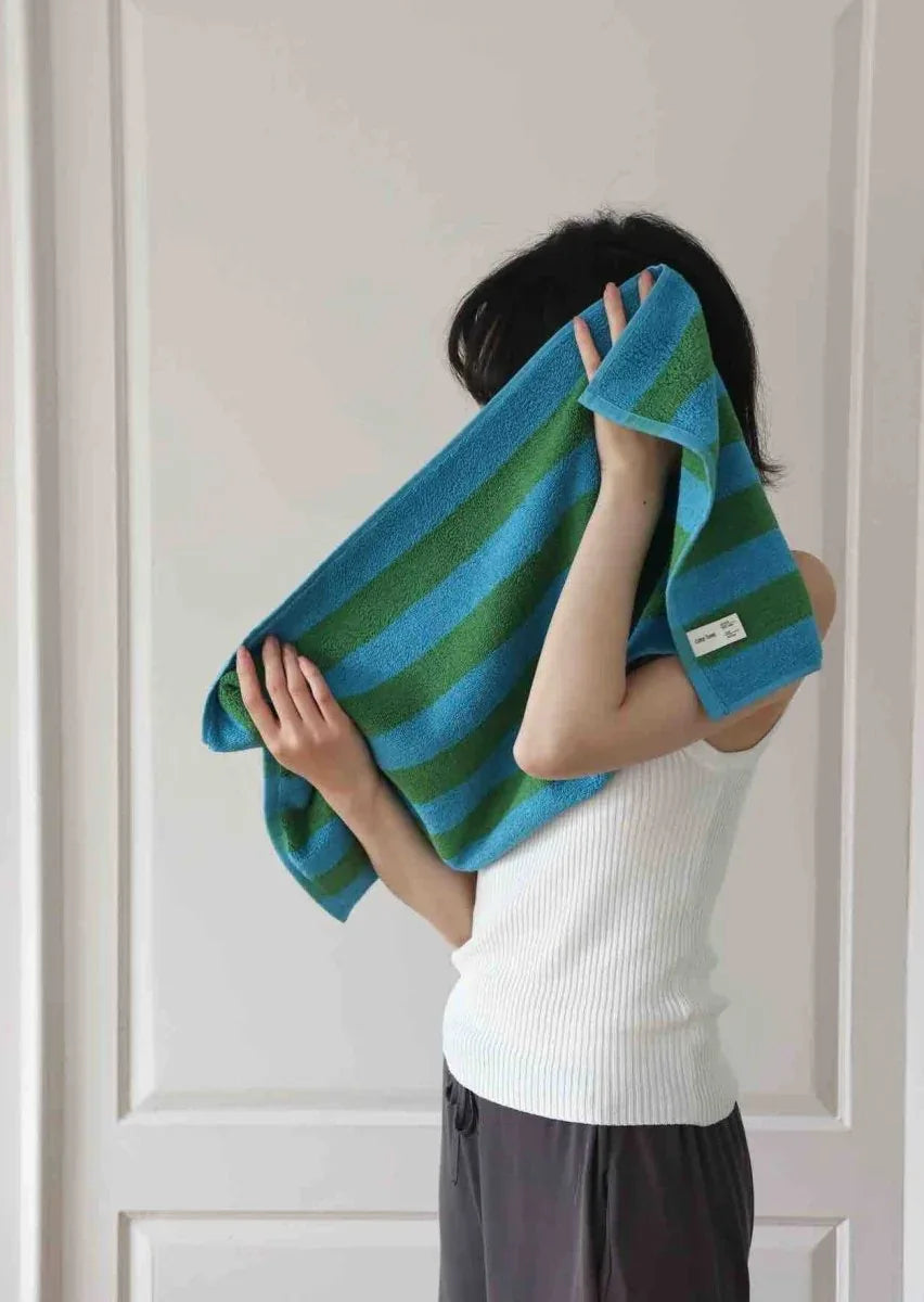 Bath towel featuring eye-catching retro stripes laid out, showing texture and color.