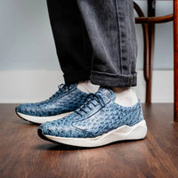 On-foot view of navy blue luxury sneaker made from genuine ostrich skin worn with dark pants.